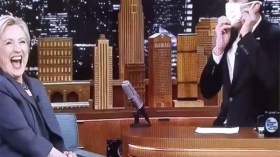 مذيع يستقبل هيلاري كلينتون بالقناع الطبي