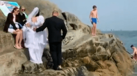 عروسان يحتفلان بزواجهما بالقفز في البحر بملابس الزفاف