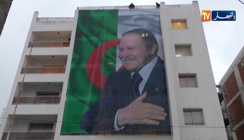 لحظة إسدال صورة الرئيس بوتفليقة على مقر حملته الرئيسي