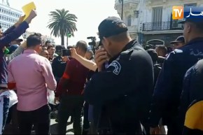 شاهد..شرطي يتمعّن ويقرأ في شعار يحمله أحد الطلبة !!